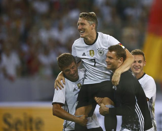 Germany's Thomas Mueller and Manuel Neuer bid farewell to Bastian Schweinsteiger after his final international match