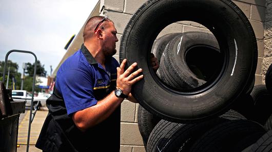 A mechanic stacks used tires outside the service bay of a Goodyear Tire & Rubber Co. auto garage in Shelbyville Kentucky