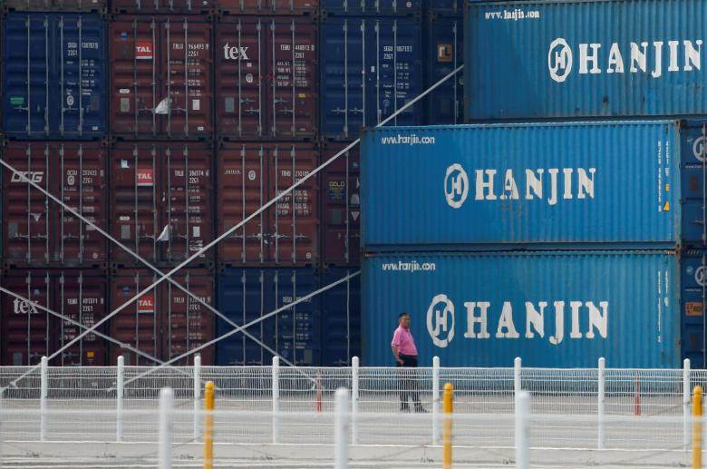 A man stands in front of shipping containers at the Hanjin Shipping container terminal at Incheon New Port in Incheon