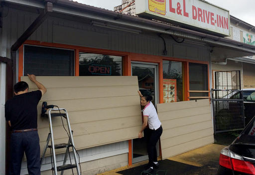 Kaly Sun right removes boards from her restaurant in Pahoa Hawaii after Tropical Storm Madeline moved through the area Thursday Sept. 1 2016. The tropical storm left parts of Hawaii's Big Island soggy but intact as residents of the island state prep