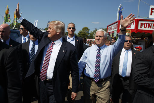 Republican presidential candidate Donald Trump center left waves as he walks with vice presidential candidate Gov. Mike Pence R-Ind. center right during a visit to the Canfield Fair Monday Sept. 5 2016 in Canfield Ohio