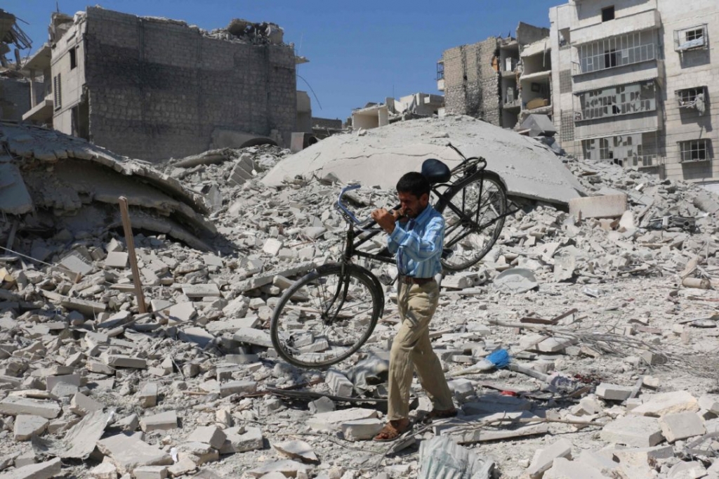 A Syrian man carryies a bicycle through the rubble of destroyed buildings in Aleppo on Sept 11 2016 the day before the U.S.-Russia negotiated ceasefire came into effect