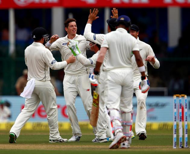 New Zealand's Mitchell Santner celebrates with teammates after taking the wicket of India's