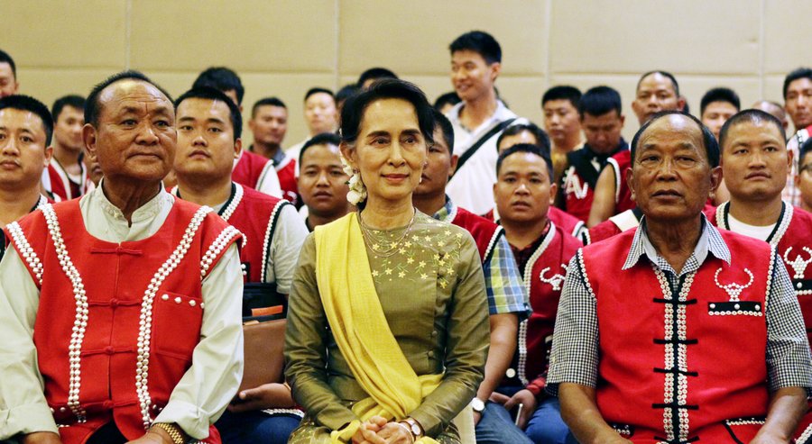 Myanmar's Foreign Minister Aung San Suu Kyi center sits with members of the United Wa State Army as they pose for