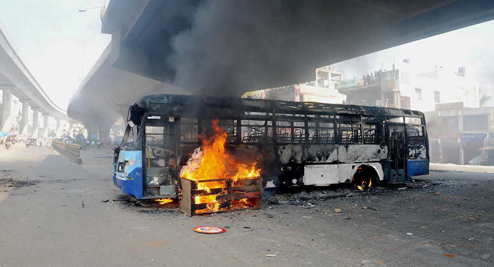 A bus burns underneath an flyover following a protest by Indian garment factory workers in Bangalore