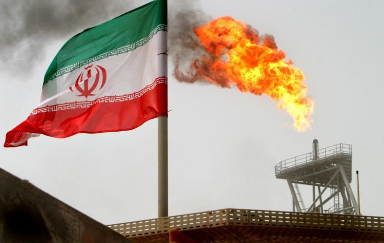 A gas flare on an oil production platform is seen alongside an Iranian flag in the Gulf