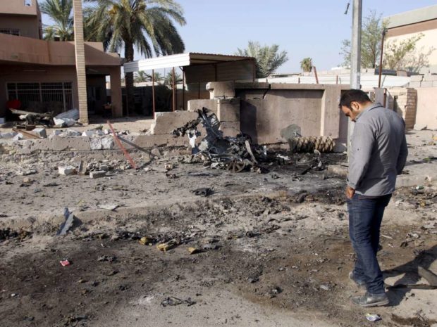 A resident inspects the site of car bomb attack in Baghdad