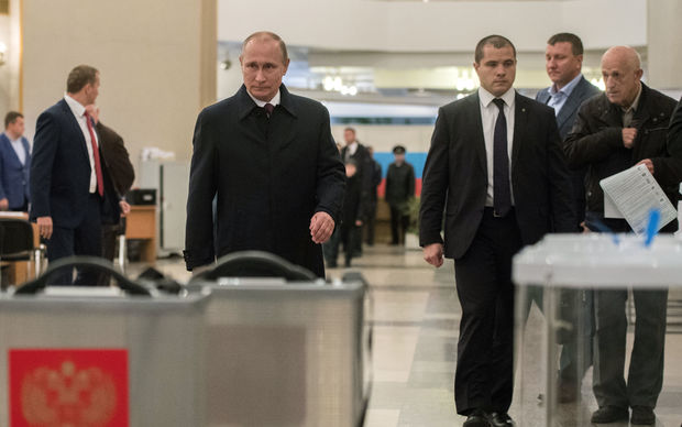 Russian President Vladimir Putin foreground left casts his vote at Polling Station No. 2151 at the Russian Academy of Sciences on Unified Election Day