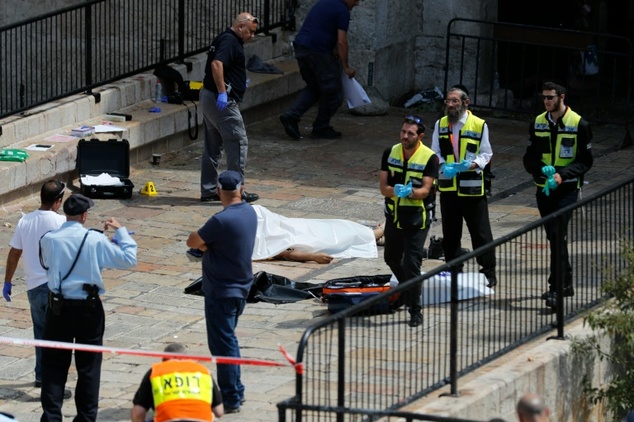 Israeli forensic policemen gather around the body of a Palestinian assailant shot dead following a reported attack at the entrance to the Old City of Jerusal