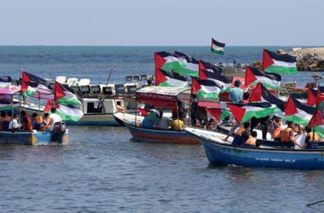 Palestinians hold their national flag as they ride boats during a rally to show support for activists aboard a flotilla of boats who are soon to set sail for Gaza in a fresh bid to break Israel's blockade at the seaport of Gaza