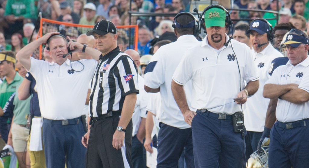 Former Irish defensive coordinator Brian VanGorder green hat watches his defense while head coach Brian Kelly