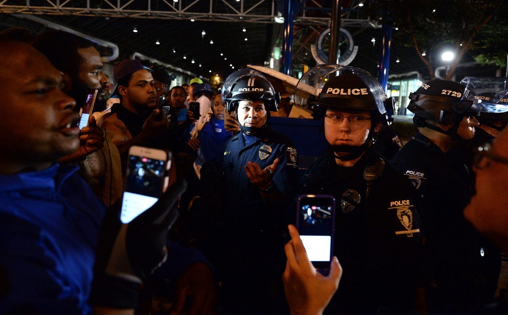 A CMPD officer center speaks with protesters in Charlotte N.C. Wednesday Sept. 21 2016. Authorities in Charlotte tried to quell public anger Wednesday after a police officer shot a black man but a dusk prayer vigil turned into a second night of vio