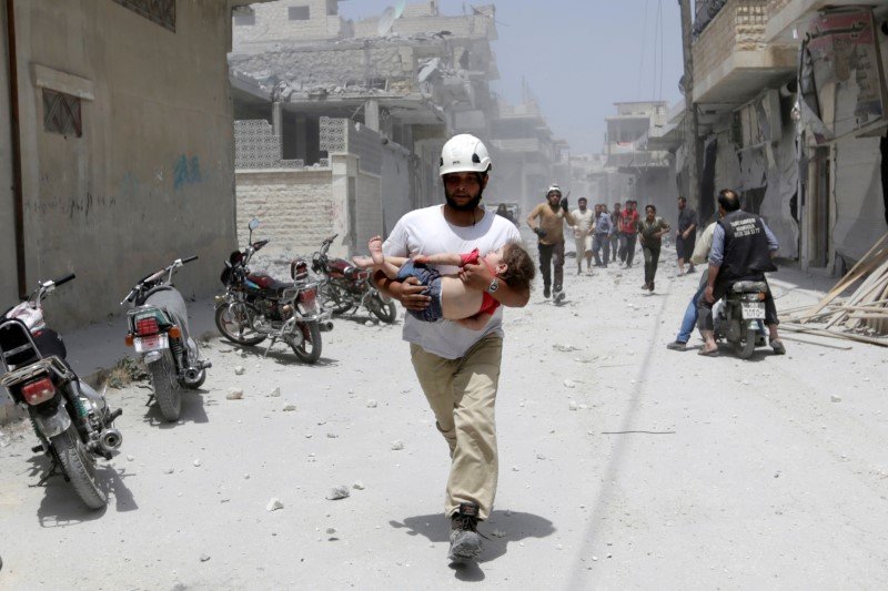 A civil defence member carries an injured girl at a site hit by airstrikes in the rebel-controlled area of Maaret al Numan town in Idlib province Syria. REUTERS  Khalil Ashawi