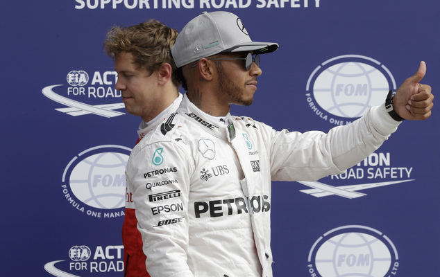 Mercedes driver Lewis Hamilton right of Britain celebrates after setting the fastest time as third placed Ferrari driver Sebastian Vettel walks past him