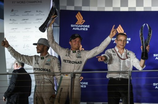 Nico Rosberg raises the trophy as he celebrates victory on the podium with second runner up Lewis Hamilton after the Singapore Grand Prix night race on Sept 18 2016. AFP