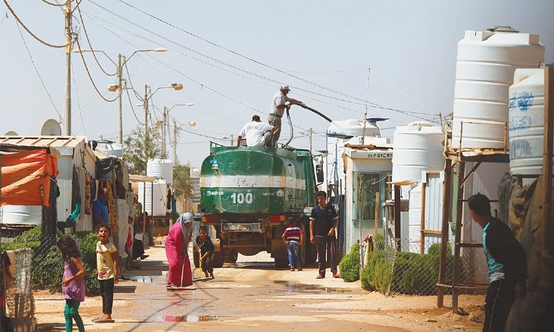 MAFRAQ: Water being topped up for Syrian refugees on Saturday in the Al Zaatri refugee camp near the border with Syria.—Reuters