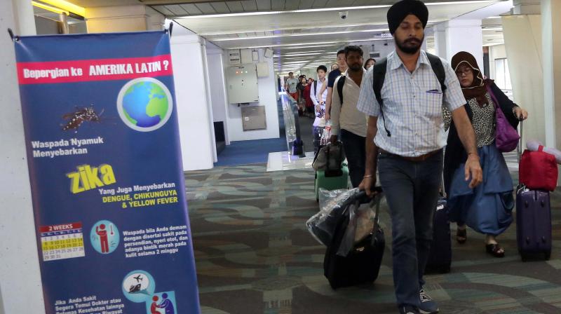 Arriving travelers walk past an information banner on Zika virus at Soekarno Hatta International Airport in Tangerang Indonesia