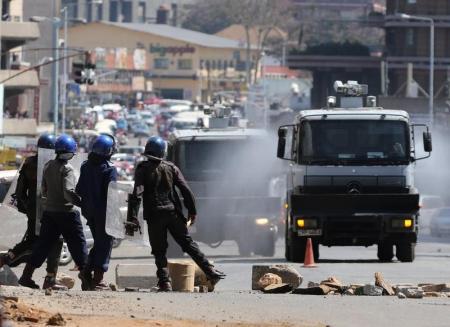 Anti-riot police clear roads during a protest by opposition youths who were demonstrating against alleged brutality by security agents in the capital Harare Zimbabwe