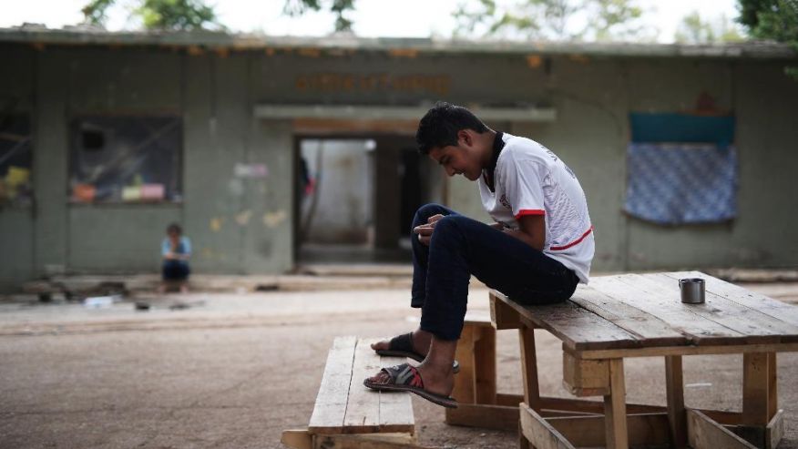 A young refugee looks at his phone in Ritsona refugee camp north of Athens which hosts about 600 refugees and migrants on Thursday Sept. 8 2016. The refugee crisis is expected to be a central issue in discussions Friday at a meeting in Athens of leade