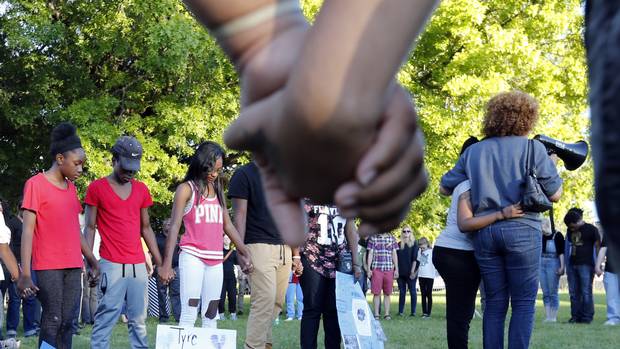 Members of Tyre King's family hold hands while listening to prayer during a vigil