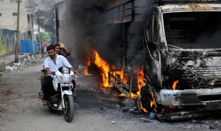 Men ride a motorcycle past a lorry in Bengaluru which was set on fire by protesters after India's Supreme Court ordered Karnataka state to release 12,000 cubic feet of water per second every day from the Cauvery river to neighbouring Tamil Nadu India Se