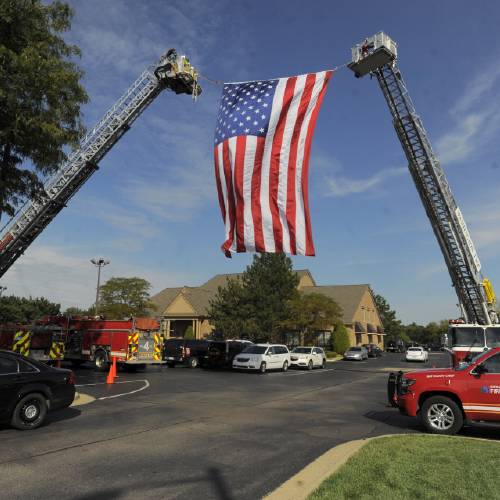 American flag is unfurled by Sterling Heights and Washington Twp. Fire Departments as mourners begin to arrive for visitation for Detroit Police officer Ken Steil in Sterling Heights Mich. Wednesday Sept. 21 2016. Steil died unexpected