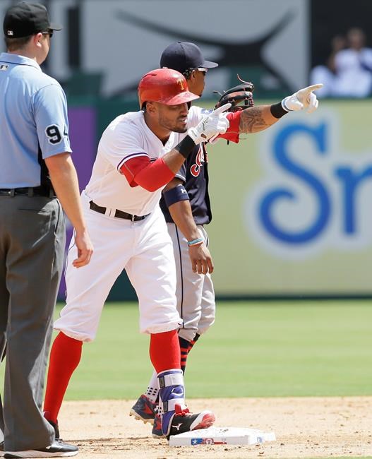 Texas Rangers&#39 Ian Desmond center celebrates an RBI while standing next to Cleveland Indians shortstop Francisco Lindor right and umpire Lance Barrett during the third inning of a baseball game in Arlington Texas Sunday Aug. 28 2016. Rang