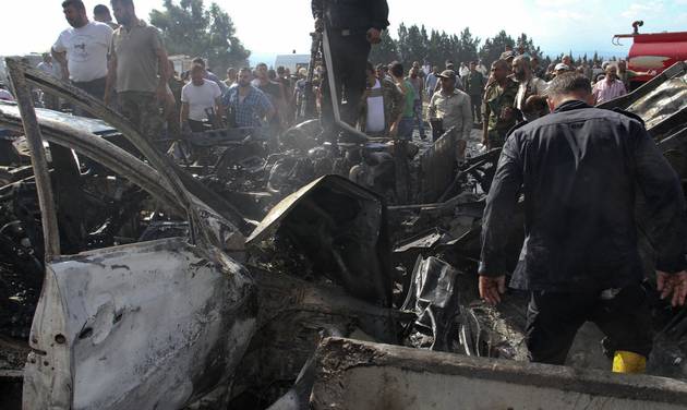 Syrian official news agency SANA Syrian security forces emergency services and residents look at the remains of burned vehicles at the site of a bombing in Tartus Syria Monday Sept. 5 2016. Syrian state media reported