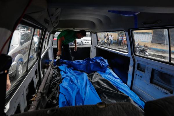 31 August 2016 shows a Filipino funeral worker stacking bodies inside a van after five alleged drug dealers were killed in a police operation in Manila Philippines 28 August 2016. E.P.A