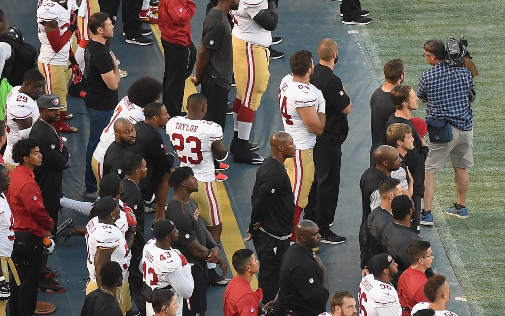 SAN DIEGO CA- SEPTEMBER 01 Colin Kaepernick #7 of the San Francisco 49ers takes a knee on the sidelines as military personel hold a flag during the singing of the National Anthem before a preseason game against the San Diego Chargers at Qualcomm Stadi