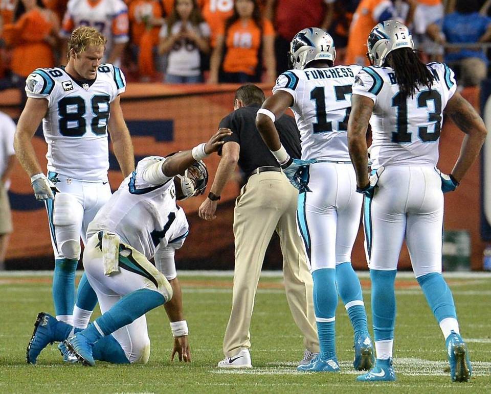 Carolina Panthers tight end Greg Olsen from left watches as quarterback Cam Newton steadies himself on head athletic trainer Ryan Vermillion's left arm as he slowly gets to his knees