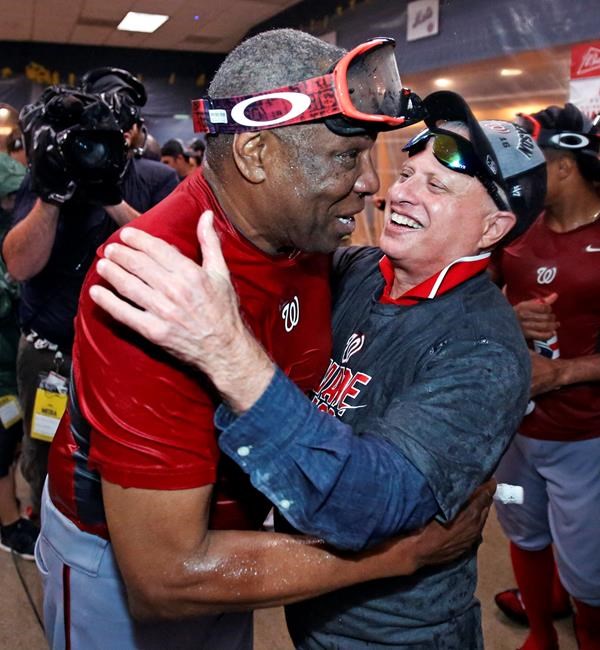 Washington Nationals manager Dusty Baker left gets a hug from Nationals principal owner Mark D. Lerner while celebrating in the locker room after clinching the National League East following a 6-1 win over the Pittsburgh Pirates in a baseball game in Pi