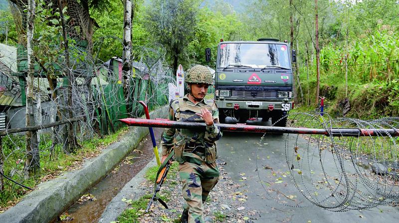 A soldier lifts an iron barricade to allow a vehicle to drive out of a military base at Braripora on Wednesday