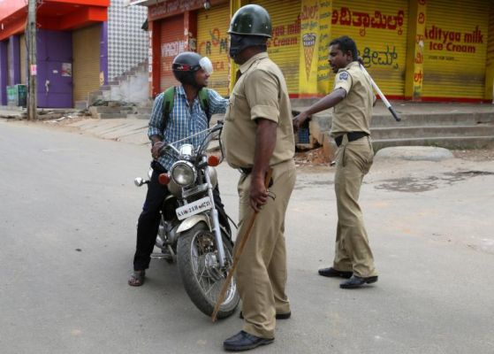 An Indian policeman hits a motorcyclist for defying