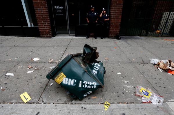 A mangled dumpster sits on the sidewalk