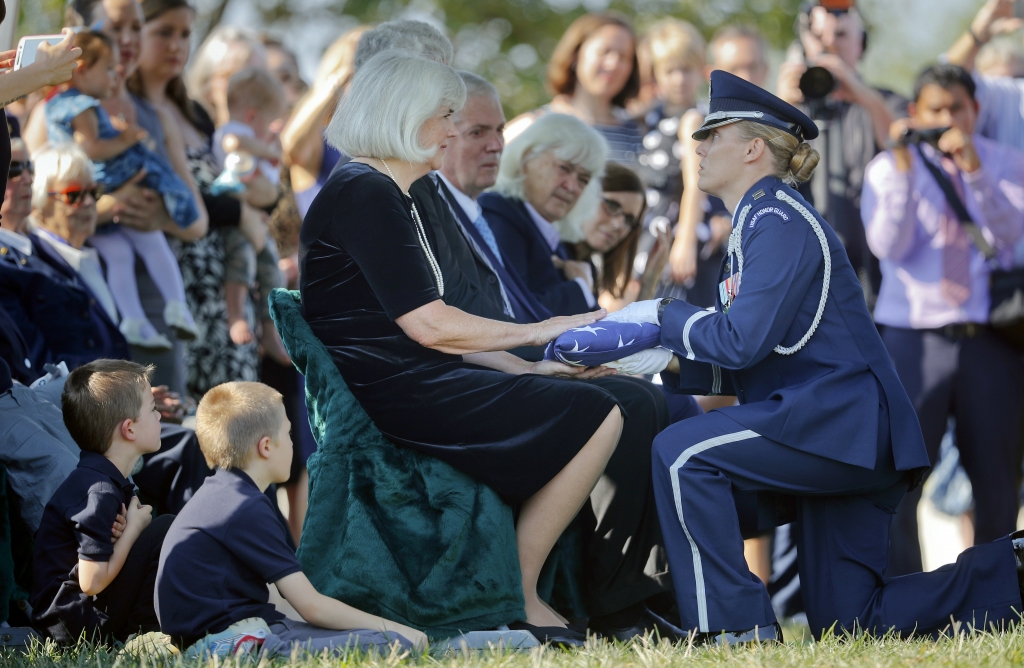 Air Force Capt. Jennifer Lee right kneels as she presents an American flag to Terry Harmon center seated daughter of World War II pilot Elaine Danforth Harmon during burial services Wednesday Sept. 7 2016 at Arlington National Cemetery in Arlingto