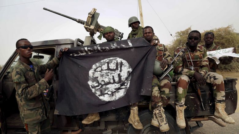 Nigerian soldiers hold up a Boko Haram flag that they had seized in the recently retaken town of Damasak Nigeria