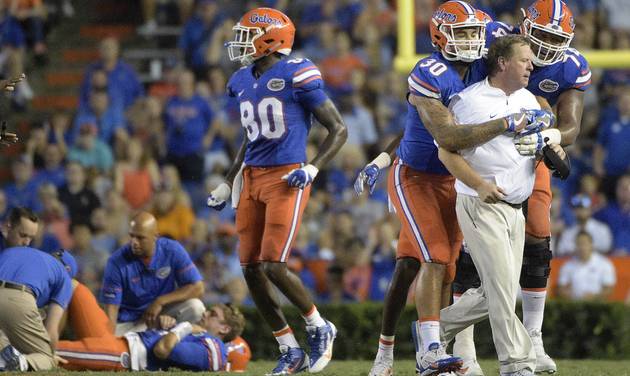 Florida coach Jim Mc Elwain is restrained by tight end De Andre Goolsby and offensive lineman Fred Johnson after Mc Elwain showed his displeasure after quarterback Luke Del Rio left was knocked out of the game during the second half of an NCAA