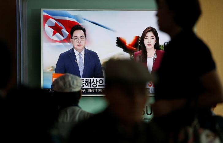 Passengers watch a TV screen broadcasting a news report on North Korea firing three ballistic missiles into the sea off its east coast at a railway station in Seoul South Korea