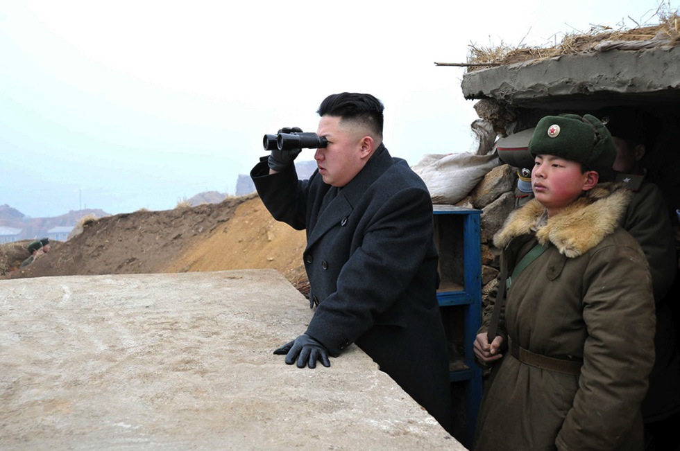 North Korean leader Kim Jong Un center uses binoculars to look at the South's territory from an observation post. Pic AP