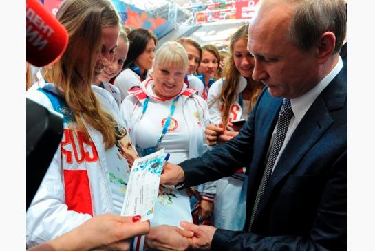 Russian President Vladimir Putin right signs autographs during his meeting with Russian athletes before the opening ceremony of the World Swimming Championships at the Kazan Arena stadium in Kazan Russia