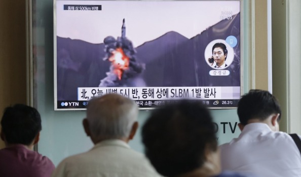 People watch a TV news program showing file footage of North Korea launching missiles in its latest provocation