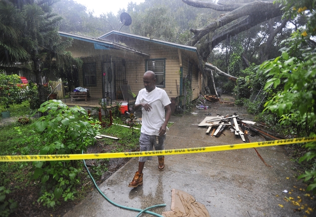 Andre Anton stops from gathering his families belongings as the rain continues pour inside of his home after a large tree crashed through the roof Wednesday