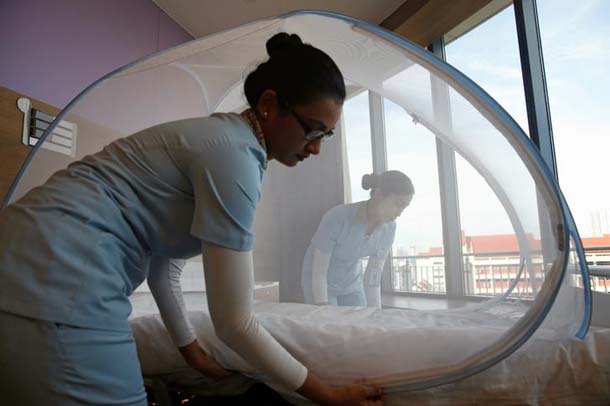 Nurses set up a mosquito tent over a hospital bed as part of a precautionary protocol for patients who are infected by Zika to show the media at Farrer Park Hospital in Singapore