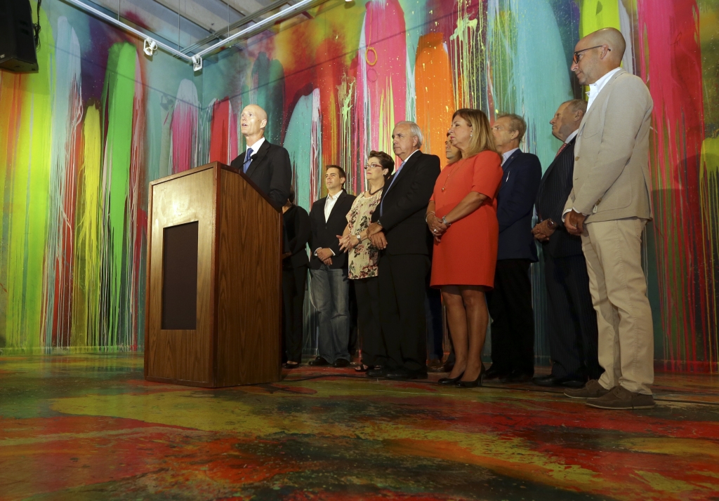 Florida Gov. Rick Scott left speaks during a news conference at Wynwood Walls Monday Sept. 19 2016 in the Wynwood neighborhood of Miami. The governor said the arts district is no longer considered a zone of active Zika transmission. It has been 45