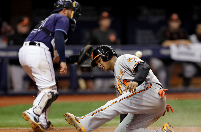 An Orioles player slides into home while a Rays catcher catches the ball