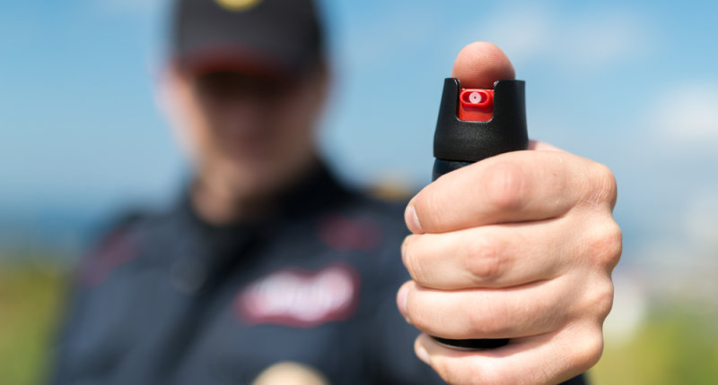 A police officer holds a can of pepper spray