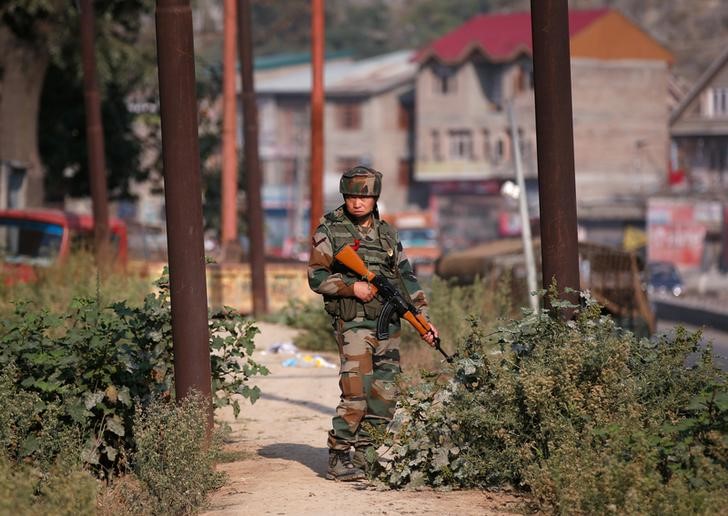 An Indian army soldier stands guard alongside a street on the outskirts of Srinagar