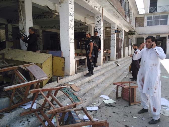 Pakistani police officials inspect the site of a suicide bomb attack at a district court in Mardan