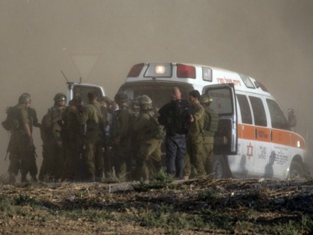 Israeli soldiers evacuate their wounded comrades at an army deployment area along the Israeli border with the Gaza Strip